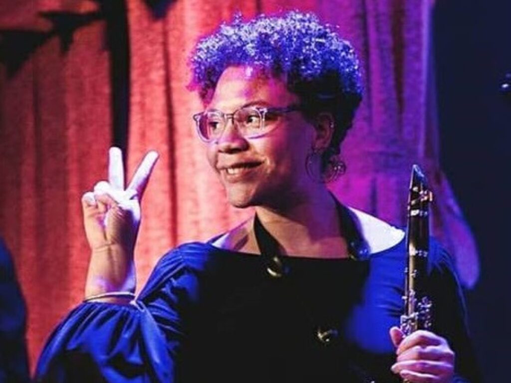 Kamila flashes the peace sign while on stage with her clarinet