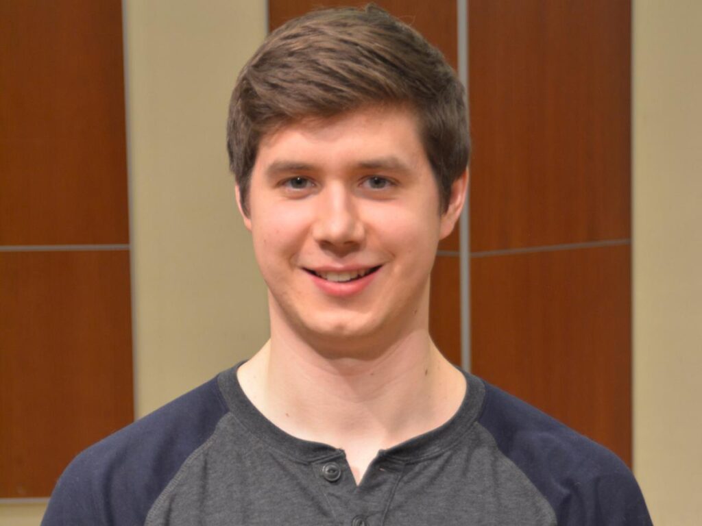 A headshot of Jacob Mezera standing on a stage