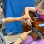 Merit students help younger kids learn about new musical instruments