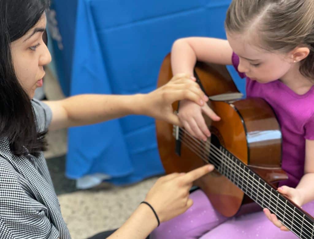 Merit students help younger kids learn about new musical instruments