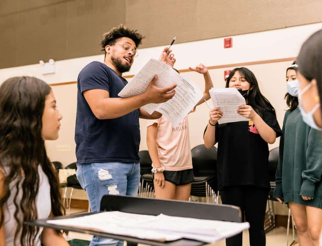 A choir teacher leads choir camp students in a song
