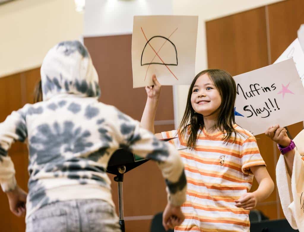 Summer camp students perform together onstage during a silly performance