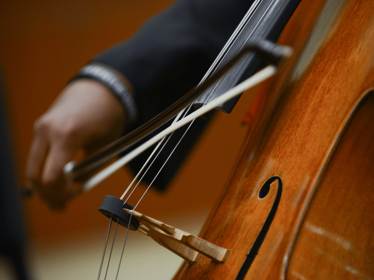 A close up shot of a cello being played, with the student's hand holding the bow.