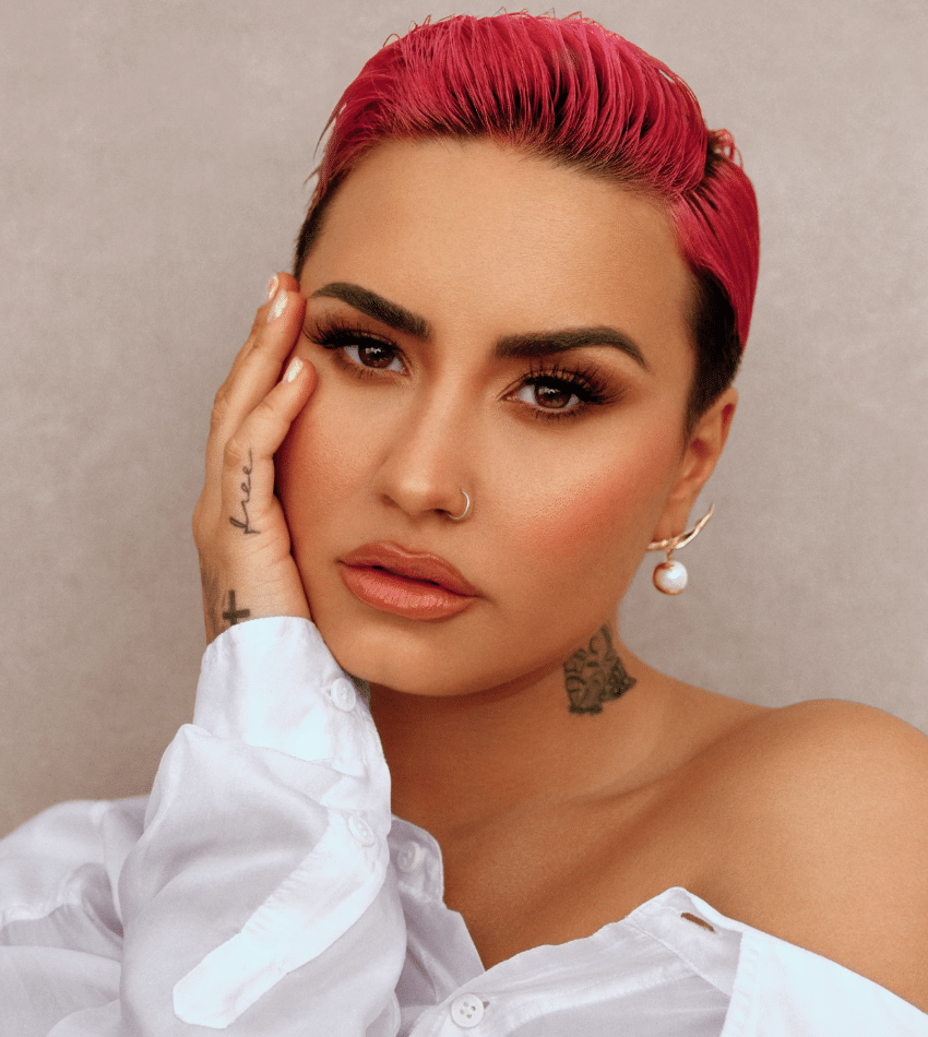 Demi Lovato poses, resting her hand on her face.