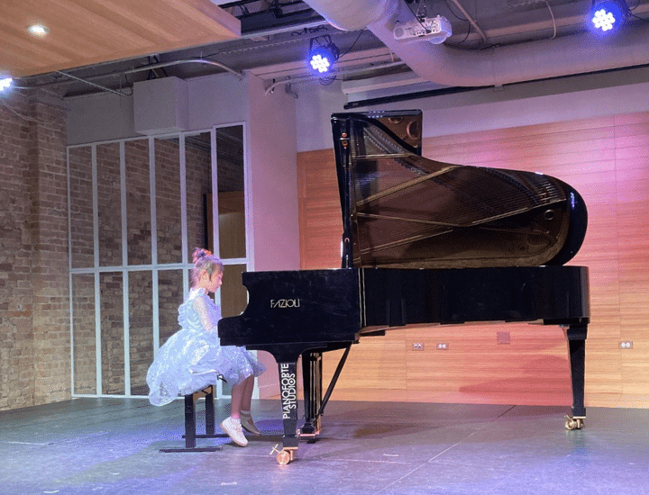 A child plays piano onstage.