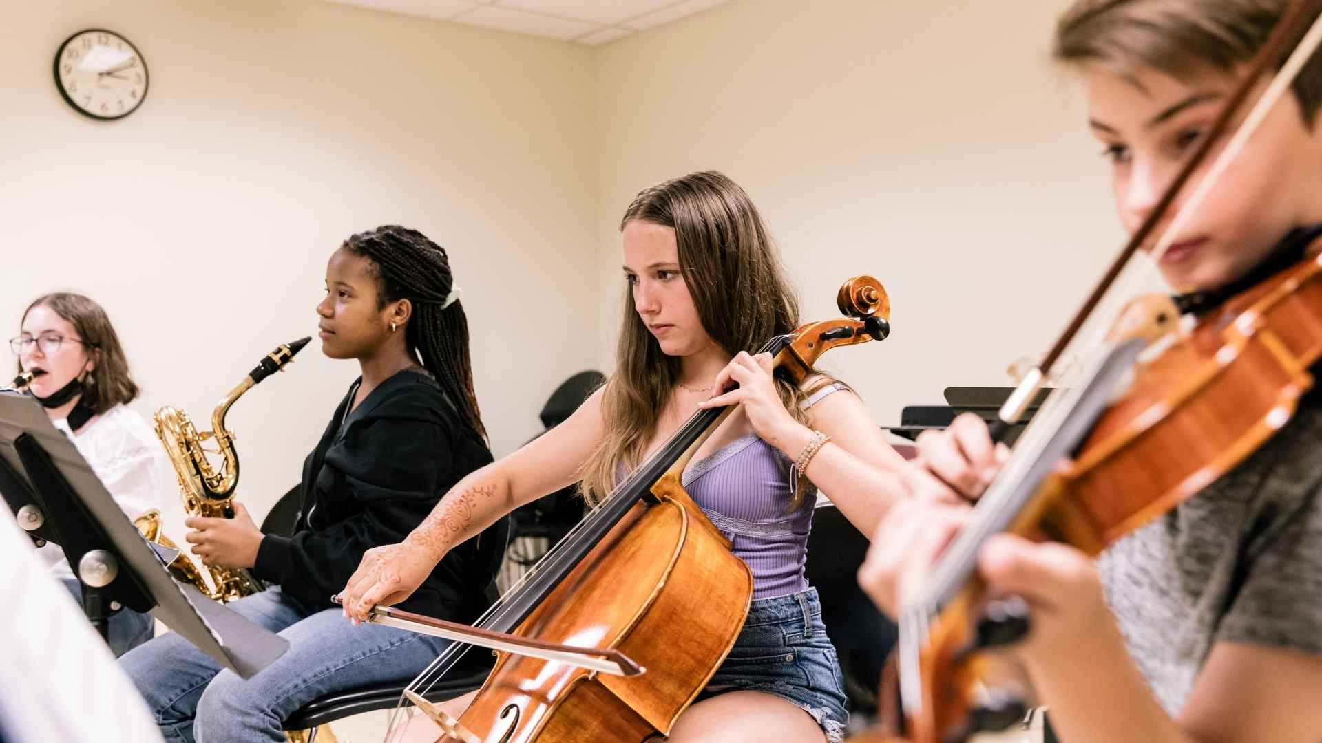 Four students playing brass instruments look at their music stands.