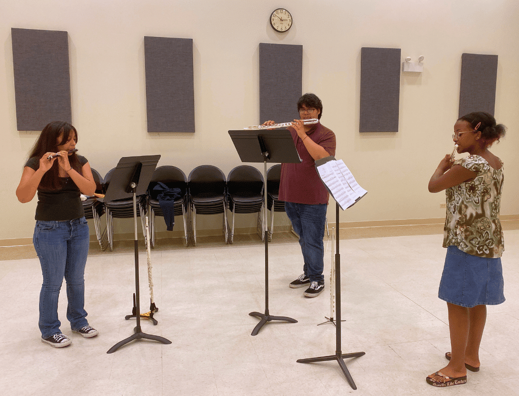 Three students rehearse together: Sofia Villanueva on piccolo, Jacob Cornejo on alto flute, and Kaylee Johnson on flute.