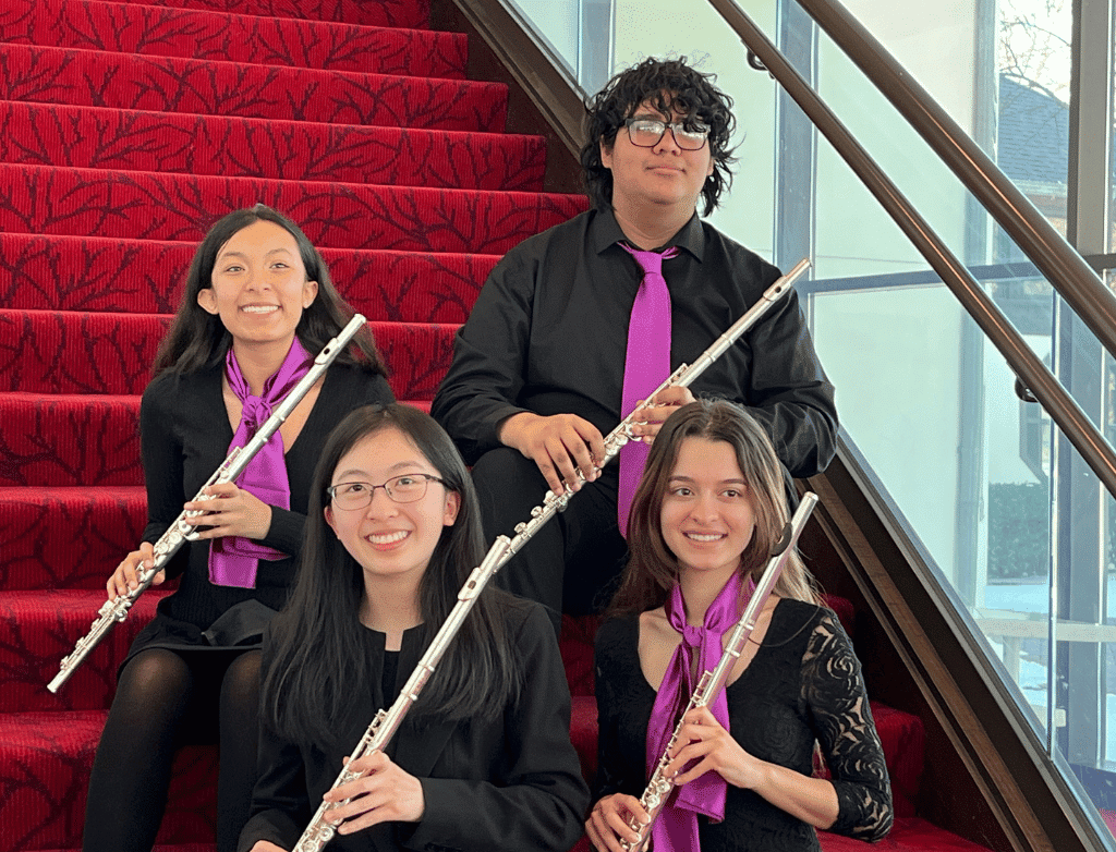 The 2021-2022 Purple Hippopotami posing with their flutes on a red staircase.