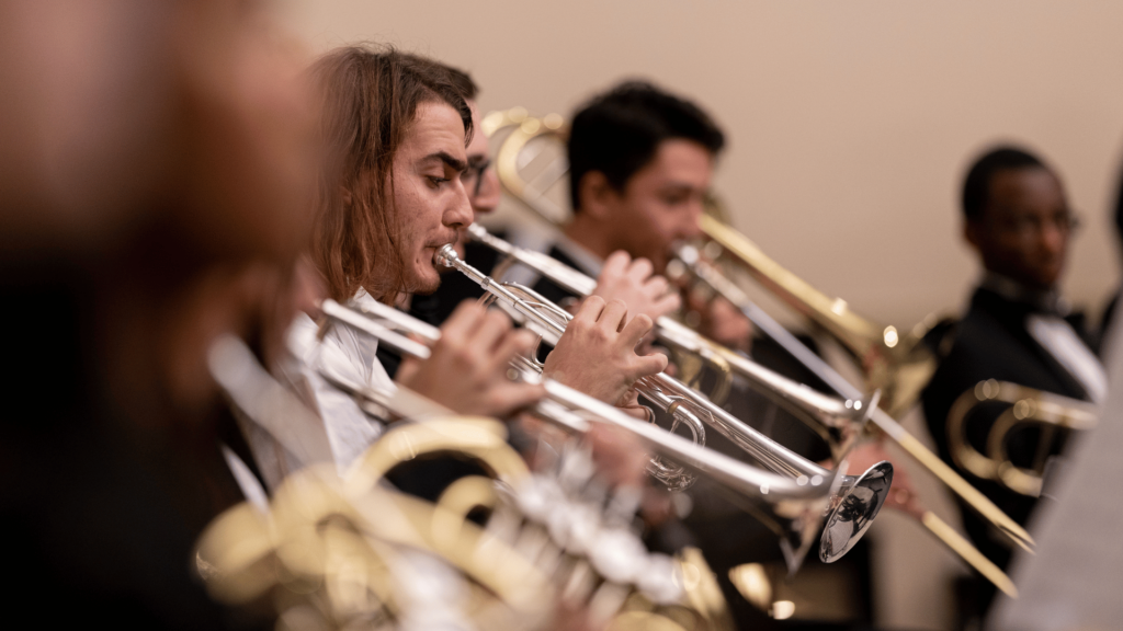 Several students play trombones and trumpets onstage.