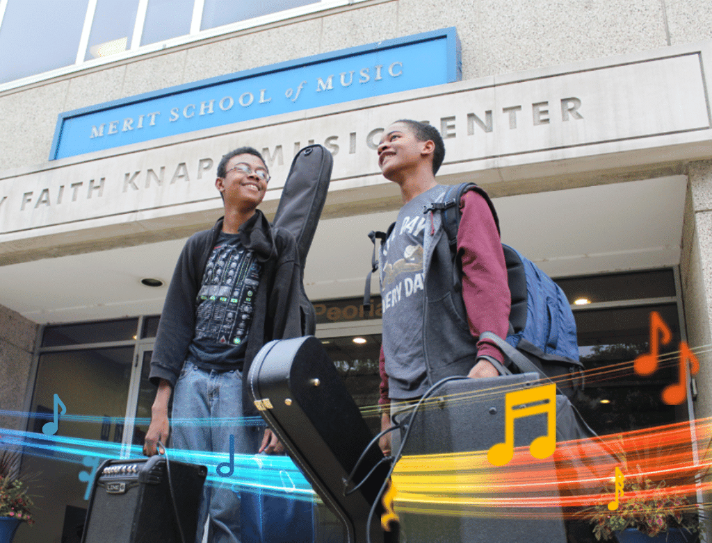 Two students stand in front of the Joy Faith Knapp Music Center, holding guitar cases and amps.
