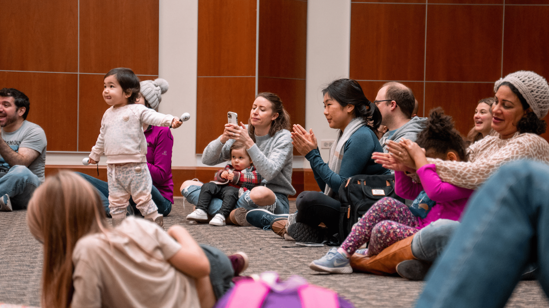 Children and parents sitting in the floor at last year's Multicultural Holiday Celebration.