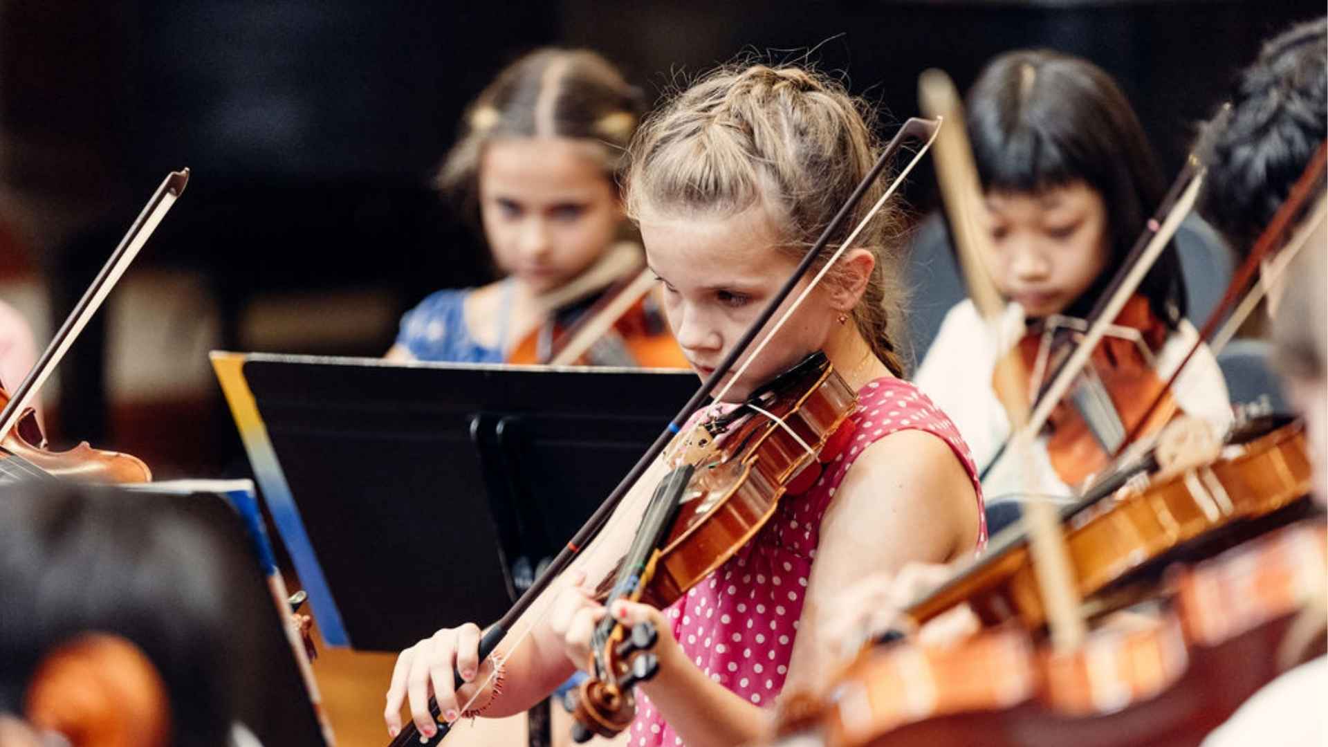 A student playing violin in an orchestra.