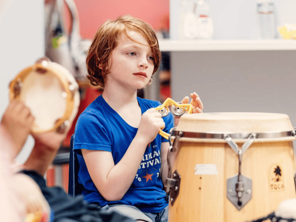 A young student plays various percussion instruments.