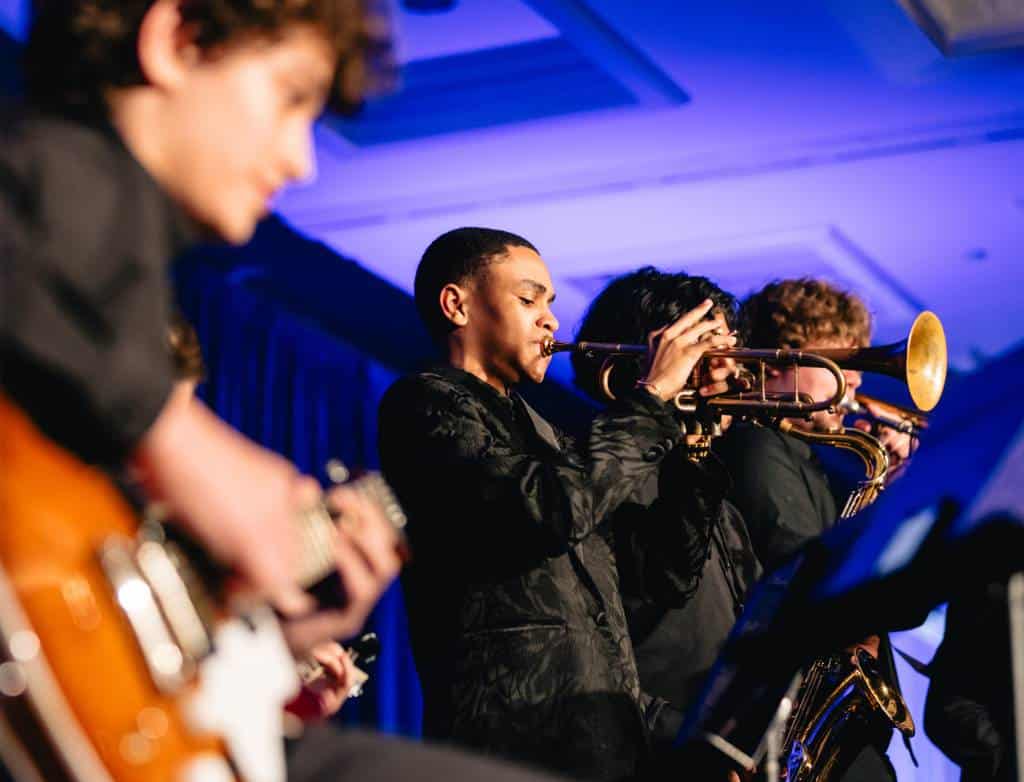 Students playing electric guitar, trumpet and saxophone
