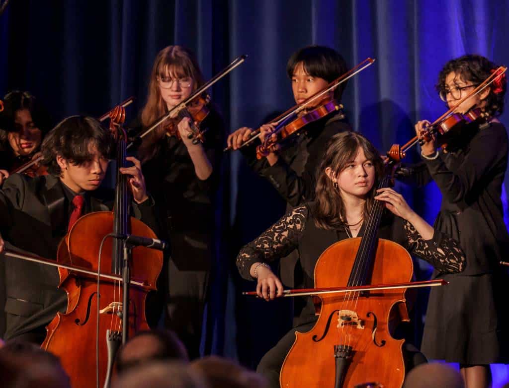 Students playing violin and cello onstage