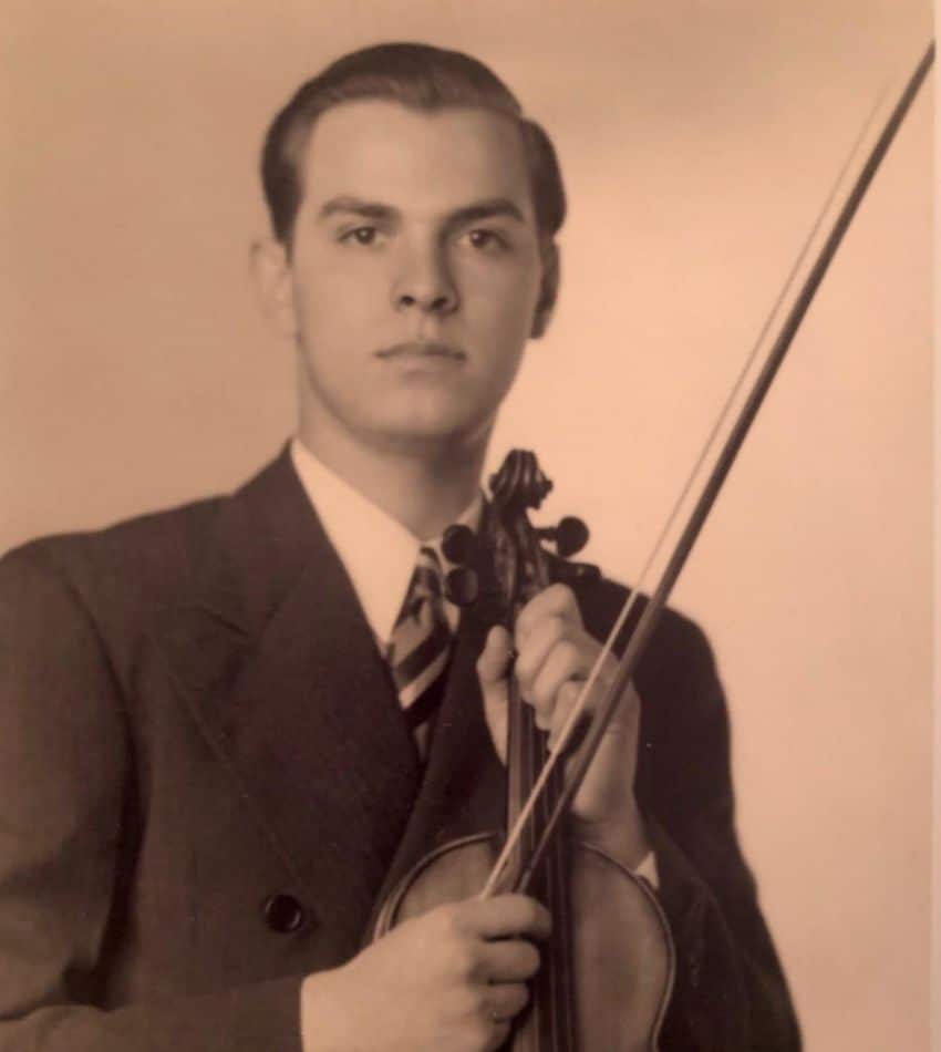 A sepia-tone photo of Howard Gottlieb as a young man, holding a violin.