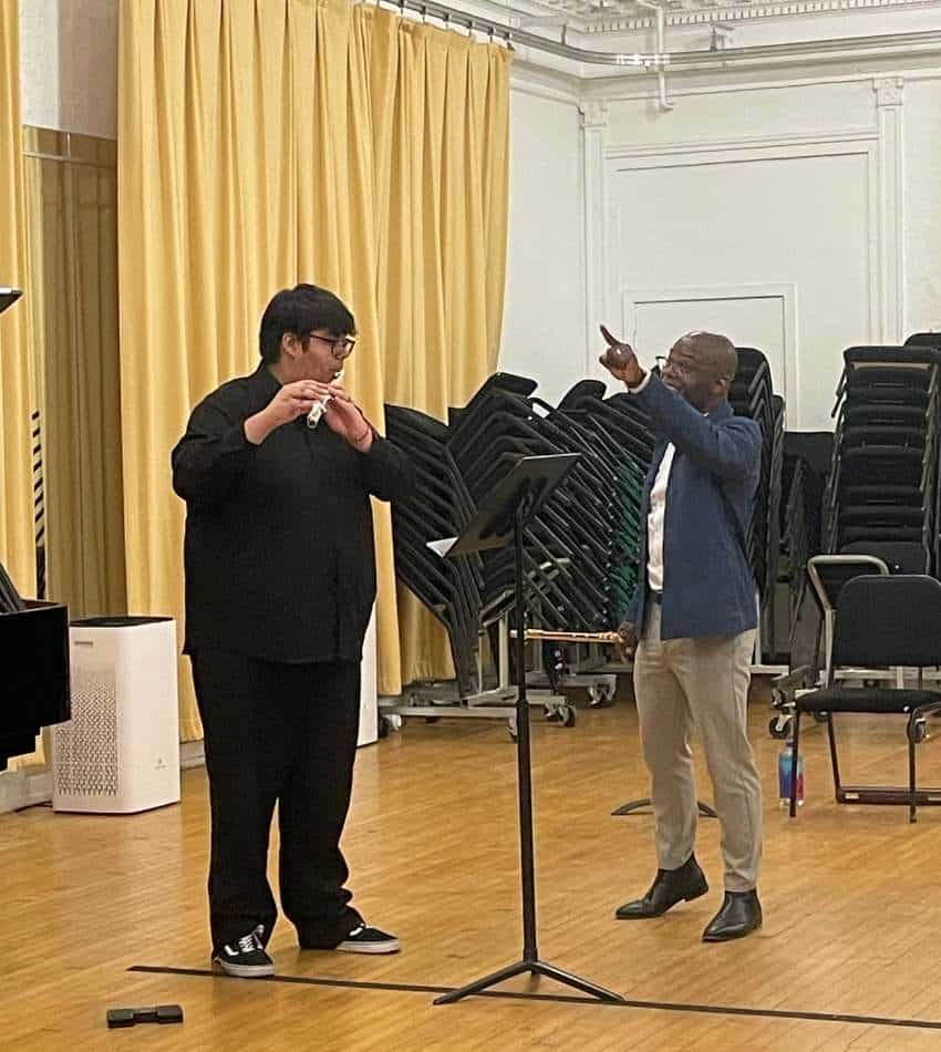 Jacob Cornejo plays flute while being coached by Demarre McGill.