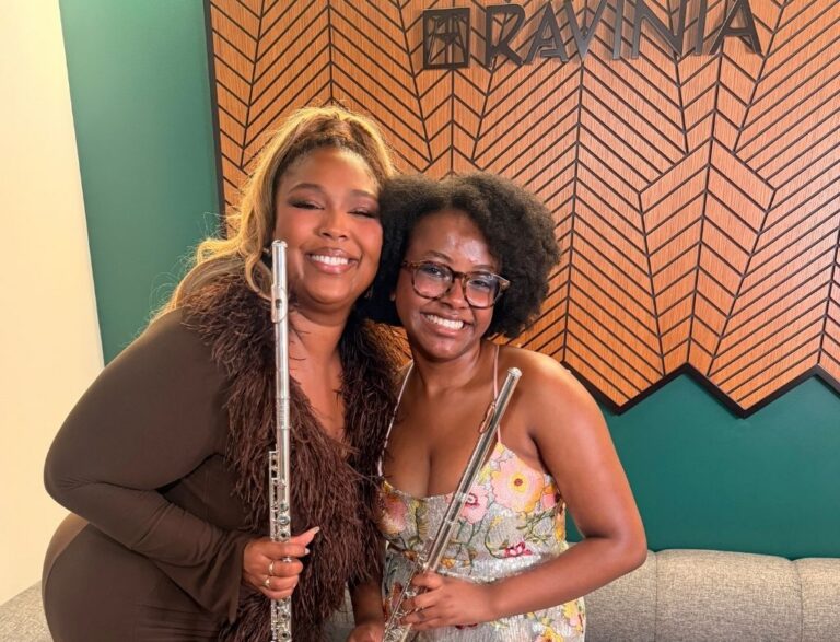 Lizzo and Kaylee smile, posing together with their flutes backstage.