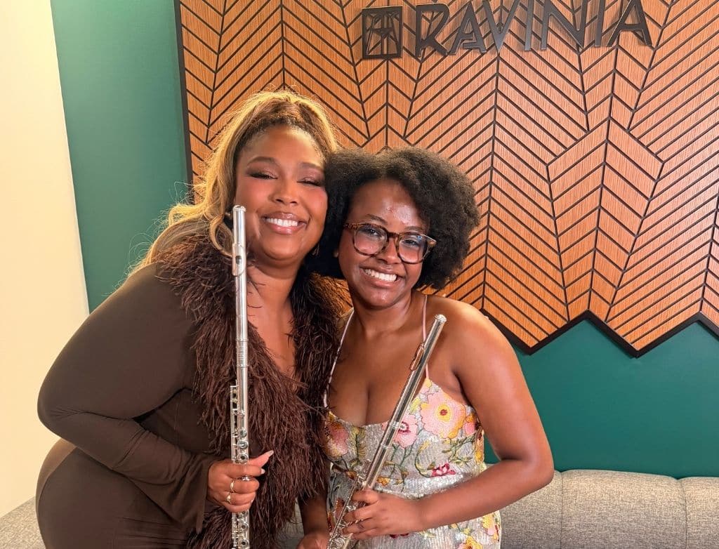 Lizzo and Kaylee smile, posing together with their flutes backstage.